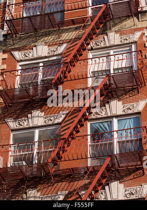 Un escalier de secours de rouge. Feu de fer peint en rouge vif s'échappe vers le bas de l'angle d'un bâtiment en briques rouges à Manhattan. Banque D'Images