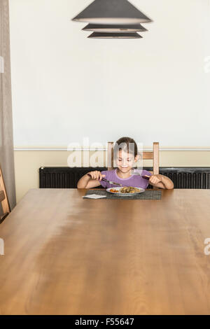 Girl de nourriture à table à manger dans la chambre Banque D'Images