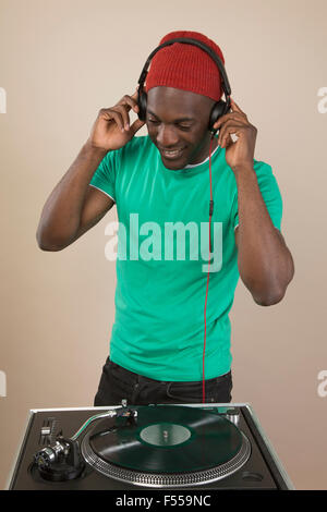 Un DJ à l'écoute au casque en face de la table rotative Banque D'Images