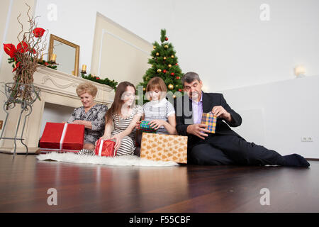Famille heureuse dans la nouvelle année donne des cadeaux sous l'arbre de Noël Banque D'Images
