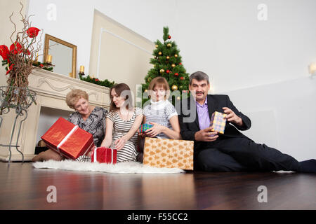 Famille heureuse dans la nouvelle année donne des cadeaux sous l'arbre de Noël Banque D'Images