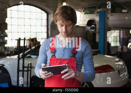Mechanic using digital tablet chez garage Banque D'Images