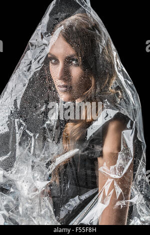 Portrait de femme enveloppée dans du plastique sur fond noir Banque D'Images