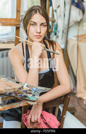 Magnifique Portrait de femme peintre assis sur une chaise en studio Banque D'Images