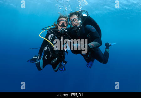 Jeune couple hanging plongeurs dans l'eau tenant les mains, de l'Océan Indien, les Maldives Banque D'Images