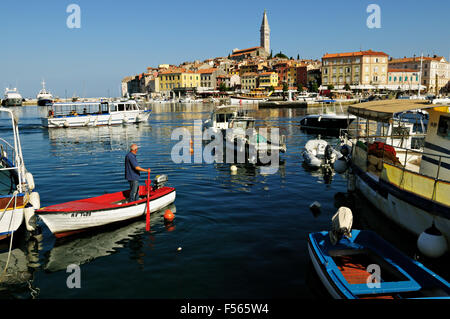 L'homme sur un petit bateau rouge et blanc dans le port de Rovinj, Istrie, Croatie Banque D'Images