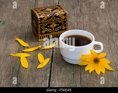 Tasse de café, des pétales, et fleur jaune, still life, sur une table en bois Banque D'Images
