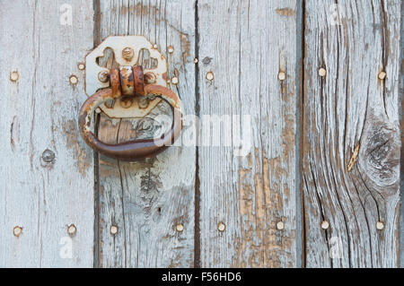 Détail d'un ancienne couronne rouillée tirer sur une poignée de porte porte en bois patiné, avec peeling a disparu de la peinture. La Drôme, France rurale. Banque D'Images