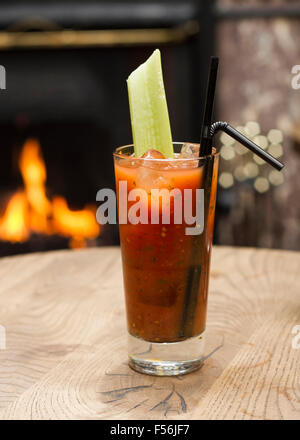 Cocktail Bloody Mary avec une branche de céleri en face d'une cheminée Banque D'Images