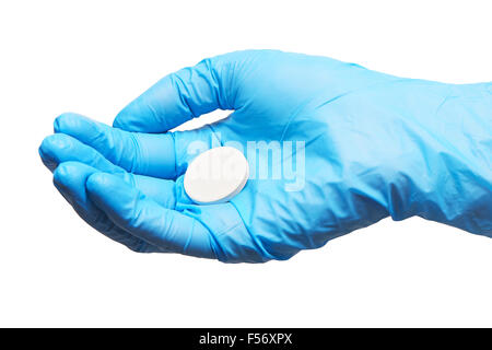 Close up of big comprimé blanc rond sur les main du médecin en bleu les gants chirurgicaux stériles contre fond blanc Banque D'Images