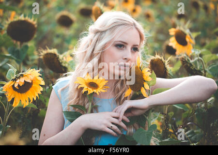 Belle jeune femme dans un champ de tournesol à l'heure d'or Banque D'Images
