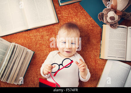 Un an bébé avec spectackles et un ours en peluche Banque D'Images