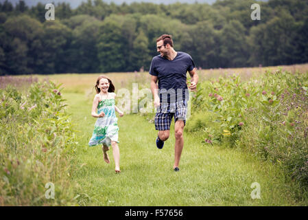 Un homme et un jeune enfant qui traverse une prairie de fleurs sauvages. Banque D'Images