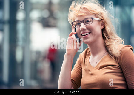 Une blonde Woman talking on a cell phone dans une rue de la ville Banque D'Images