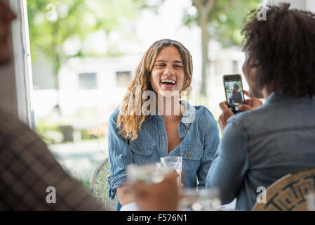 Une femme qui parle d'une photographie d'un ami à l'aide d'un téléphone intelligent. Banque D'Images