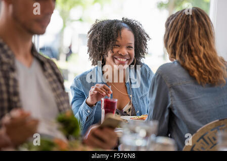 Trois personnes assises à table dans un café. Deux femmes de rire. Banque D'Images
