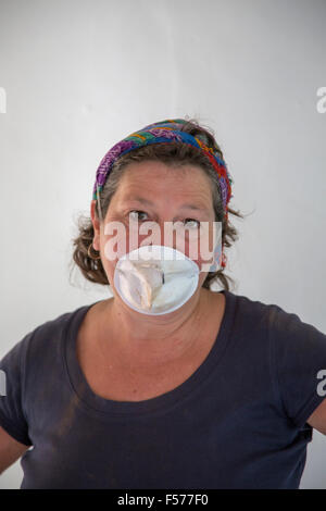 Femme d'âge moyen portant un masque DIY faire travailler à l'intérieur, England, UK Banque D'Images