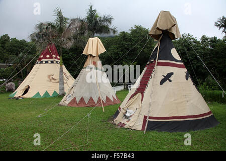 C'est une photo d'un camp indien en Amérique. Nous pouvons voir des tipis tipis ou sur l'herbe avec des forêts autour de Banque D'Images