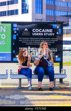 Deux jeunes femmes sont assises sur un quai de métro place en attendant le prochain tram à Minneapolis Banque D'Images