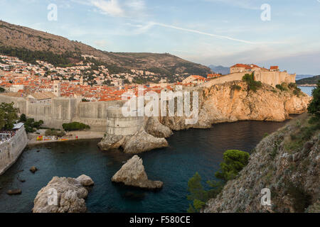 Vue sur la vieille ville et les remparts de la ville sur une falaise escarpée, à Dubrovnik, en Croatie, au coucher du soleil. Banque D'Images