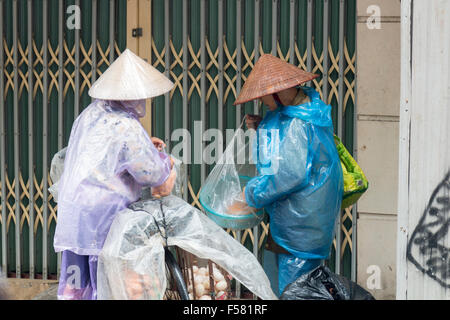 Deux vendeurs d'aliments de rue vietnamiens tri par le biais de leurs produits sur les vieux quartier de Hanoi, Vietnam Banque D'Images