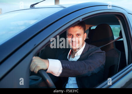 Louer une voiture, smiling happy caucasian man driving Banque D'Images