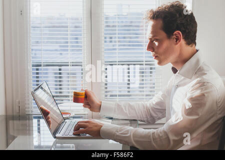 Businessman la lecture de courriers électroniques dans le bureau avec tasse de café Banque D'Images