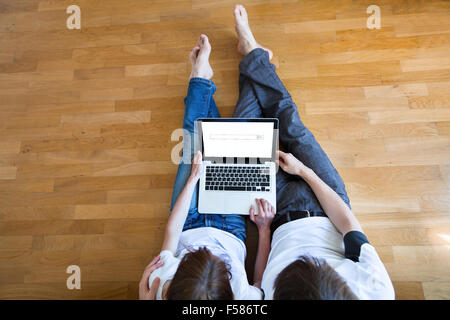 Couple assis dans leur nouvelle maison avec portable Banque D'Images