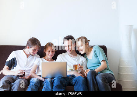 Groupe d'amis, regarder la télévision et smiling Banque D'Images