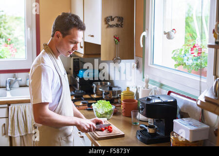 La cuisson des aliments sains, jeune homme couper les tomates dans la cuisine Banque D'Images