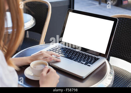 Femme à l'aide d'un ordinateur portable avec écran vide in cafe Banque D'Images