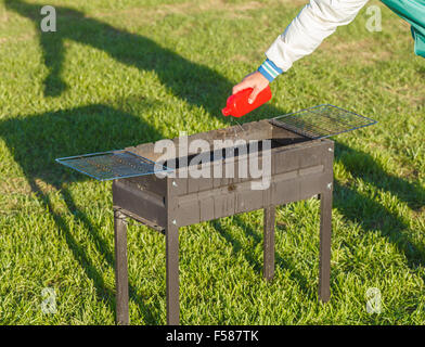 L'homme à l'aide de départ de feu liquide Barbecue Banque D'Images