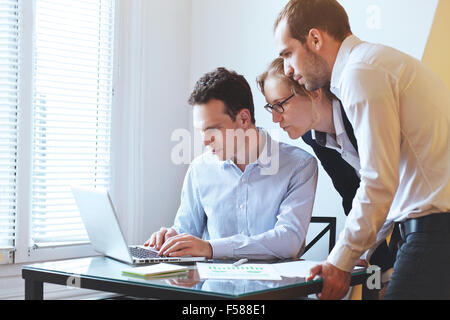 Groupe de jeunes gens d'affaires à la recherche à l'écran de l'ordinateur Banque D'Images