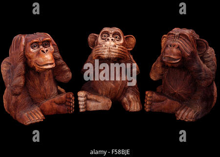 Trois Singes de la sagesse. Figurines de bois sur un fond noir. Banque D'Images