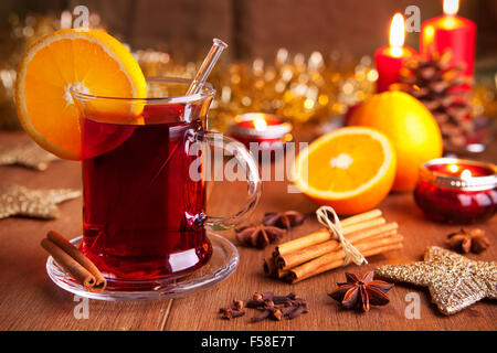 Un verre avec du vin ou vin chaud sur une table rustique avec des ingrédients et des décorations de Noël. Banque D'Images