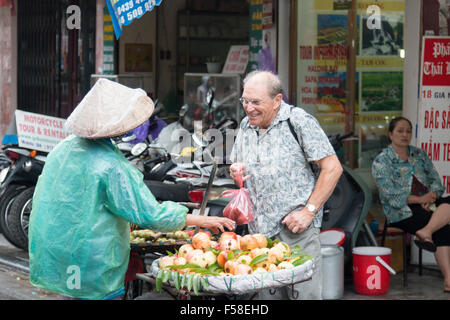 La dame vetnamaise vend des fruits à un homme occidental mature, vieux quartier de Hanoi, Vietnam, Asie Banque D'Images