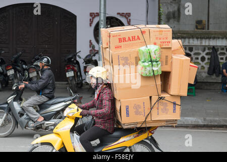 Vietnamienne sur un scooter moto transportant une charge de boîtes de carton à travers le centre-ville de Hanoi,Vietnam,asia Banque D'Images