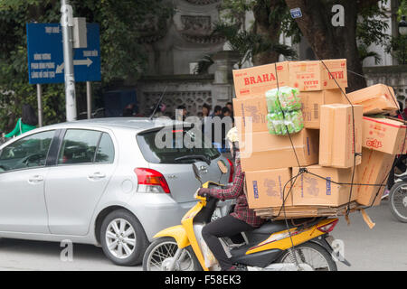 Vietnamienne sur un scooter moto transportant une charge de boîtes de carton à travers le centre-ville de Hanoi,Vietnam,asia Banque D'Images