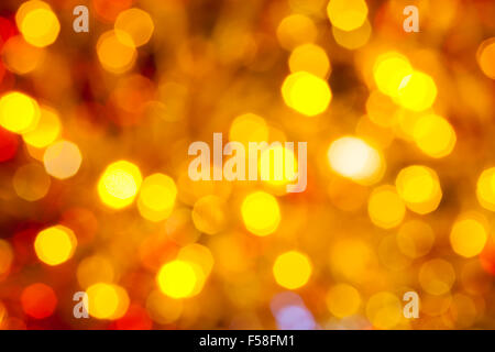 Résumé arrière-plan flou - marron, jaune et rouge, le scintillement des lumières de Noël de bokeh guirlandes électriques sur l'arbre de Noël Banque D'Images