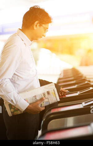 Homme d'affaires indien asiatique à l'entrée de la gare, de toucher le jeton ticket gate barrière durant le coucher du soleil, belle s'or Banque D'Images