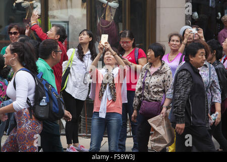 Constsntly touristes prenez des photos sur leurs téléphones à Times Square, New York City. Banque D'Images