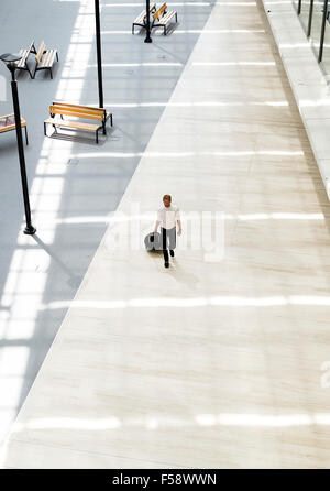 Beau business holding un chariot et la marche à pied dans un bâtiment moderne en vue d'en haut Banque D'Images