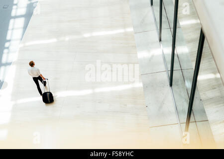 Beau business holding un chariot et la marche à pied dans un bâtiment moderne en vue d'en haut Banque D'Images