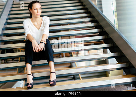 Businesswoman sitting on stairs et la pensée. Photo fashion style Banque D'Images