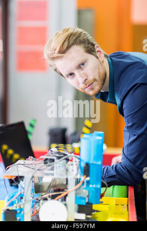 Ingénieur électrique mâle de la programmation d'un robot à la classe de robotique Banque D'Images