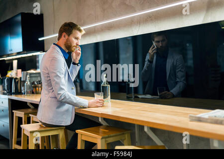 Handsome businessman et potable à l'aide d'un téléphone dans un bar Banque D'Images