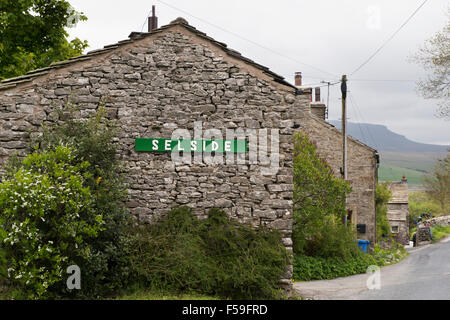 Pittoresque, traditionnelle, construite en pierre, les chalets (1) signe avec le nom du village, dans le hameau de Armoy, Yorkshire Dales National Park, England, UK. Banque D'Images