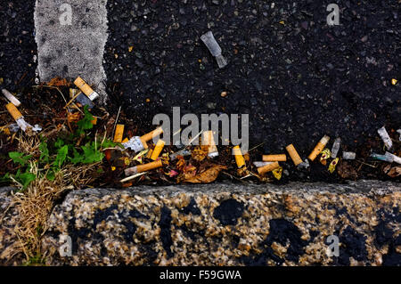 Des tas de mégots de cigarettes sur le terrain par le bord de la chaussée dans le village de Sussex de l'Ouest. Poufs Banque D'Images