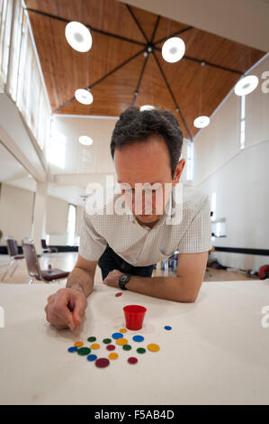 Cambridge, UK. 31 octobre, 2015. Patrick Barrie (Champion National) prend fin. La fortune anglais paires National Championships ont lieu à Selwyn College Cambridge UK. Loin d'être un jeu d'enfant, la concurrence est un mélange de stratégie et de dextérité pour propulser les "winks" à l'aide d'un "squidger" dans un pot, ou pour couvrir les opposants "winks". La naissance du jeu moderne peut être attribuée à un groupe d'étudiants de Cambridge (Royaume-Uni) en 1955. Credit : Julian Eales/ Alamy Live News Banque D'Images