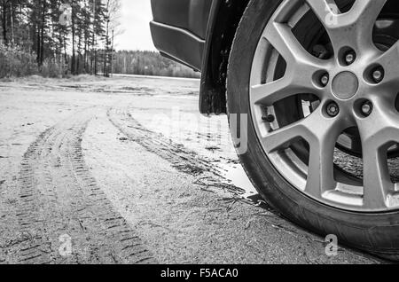 Roue de voiture avec des jantes disque sur dirty country road, Close up noir et blanc Banque D'Images